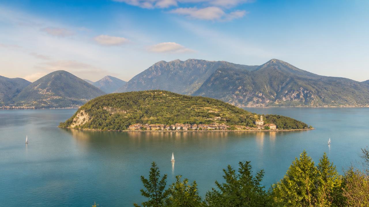 Lago Iseo i Lombardiet med Monte Isola och segelbåtar på det lugna vattnet, omgivet av gröna berg